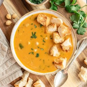A bowl of vegan garlic chickpea soup, garnished with homemade croutons.