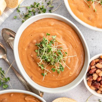 A bowl of vegan pinto bean soup topped with microgreens.