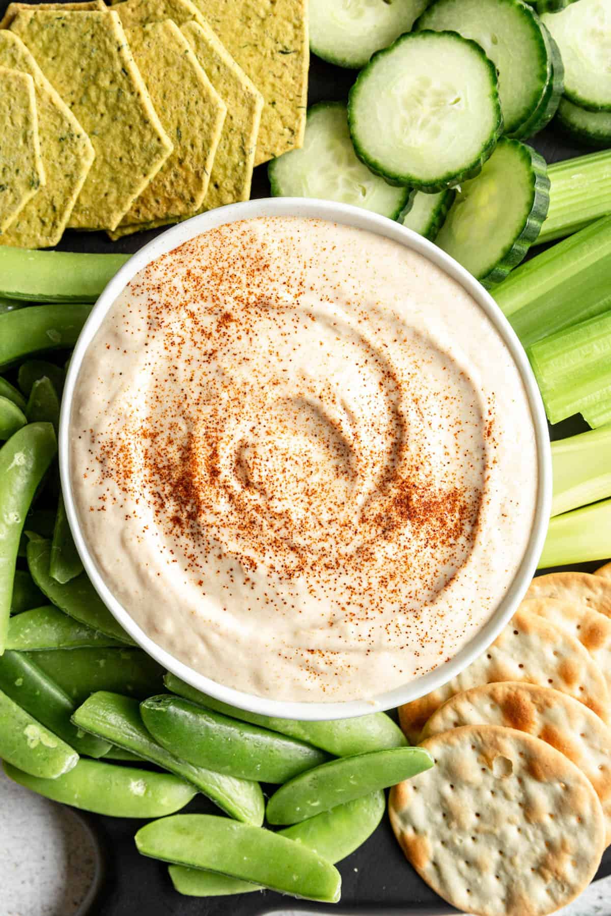 A bowl of vegan white bean dip on a tray of veggies.