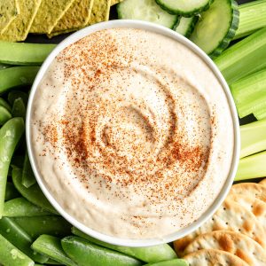 A bowl of vegan white bean dip on a tray of veggies.