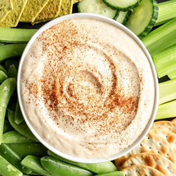 A bowl of vegan white bean dip on a tray of veggies.