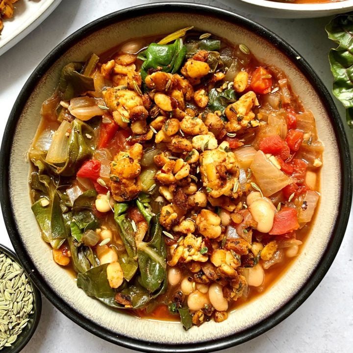 A bowl of white bean stew served with tempeh sausage.