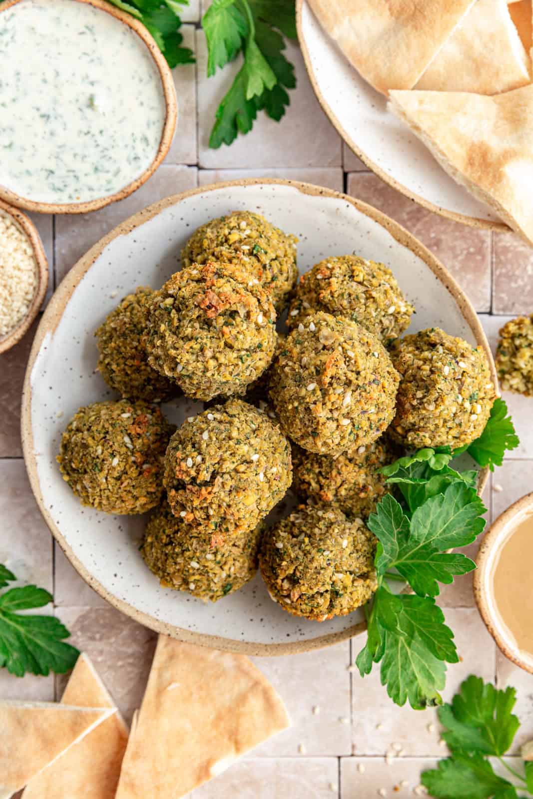 Vegan Oil-Free Falafel balls on a plate surrounded by pitas.