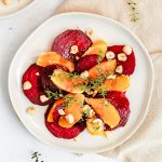 A plate of balsamic beet orange salad, topped with sprigs of fresh thyme.