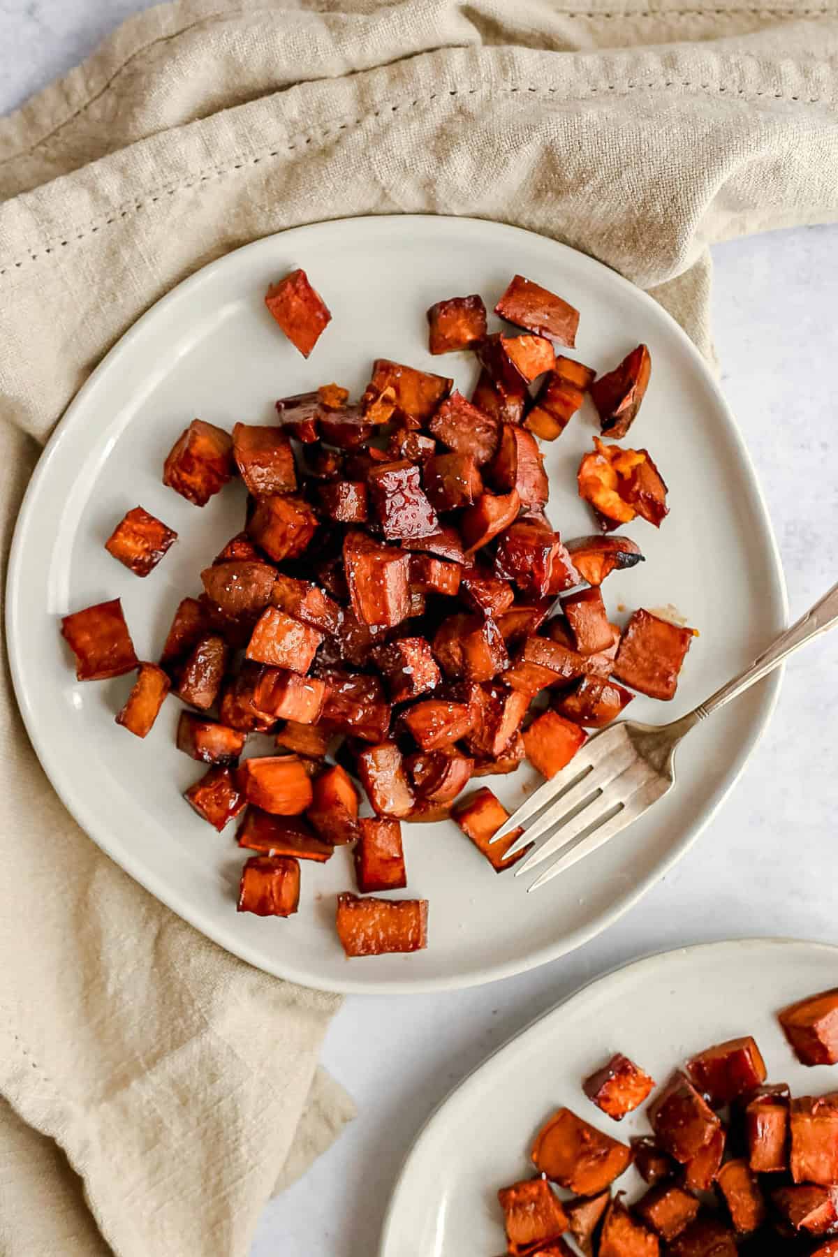 A plate of bourbon glazed sweet potatoes, with a fork, ready to serve.