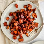 A plate of bourbon glazed sweet potatoes, with a fork, ready to serve.