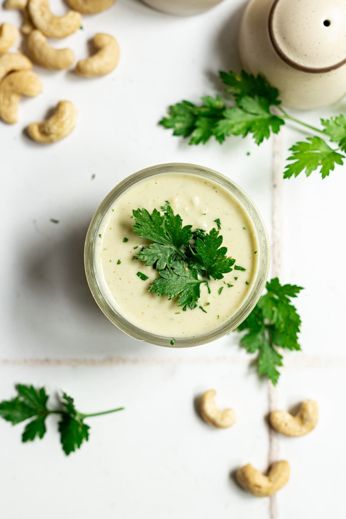 A mason jar of garlic parsley aioli, topped with a parsley leaf.