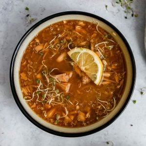 A bowl of jackfruit lemon quinoa soup, garnished with a lemon wedge.