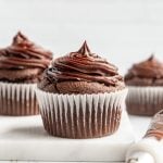 A freshly frosted cupcake on the counter, with a piping bag next to it.