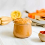 A jar of smoked paprika garlic hummus, with a plate of vegetables.