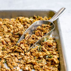A tray of sweet spicy vegan granola with a scoop full of granola.