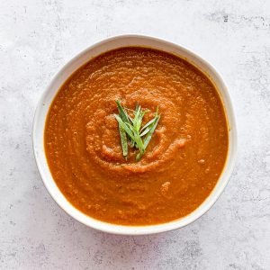 A bowl of tarragon carrot soup, garnished with tarragon.