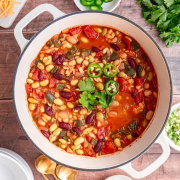 A pot of vegan tempeh chili, garnished with jalapeños and cilantro, ready to serve.