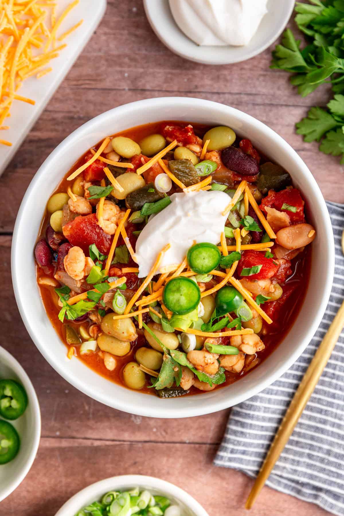 A bowl of tempeh chili, garnished with vegan cheese and vegan sour cream.