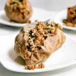 A tempeh stuffed sweet potato on a plate, garnished with parsley.
