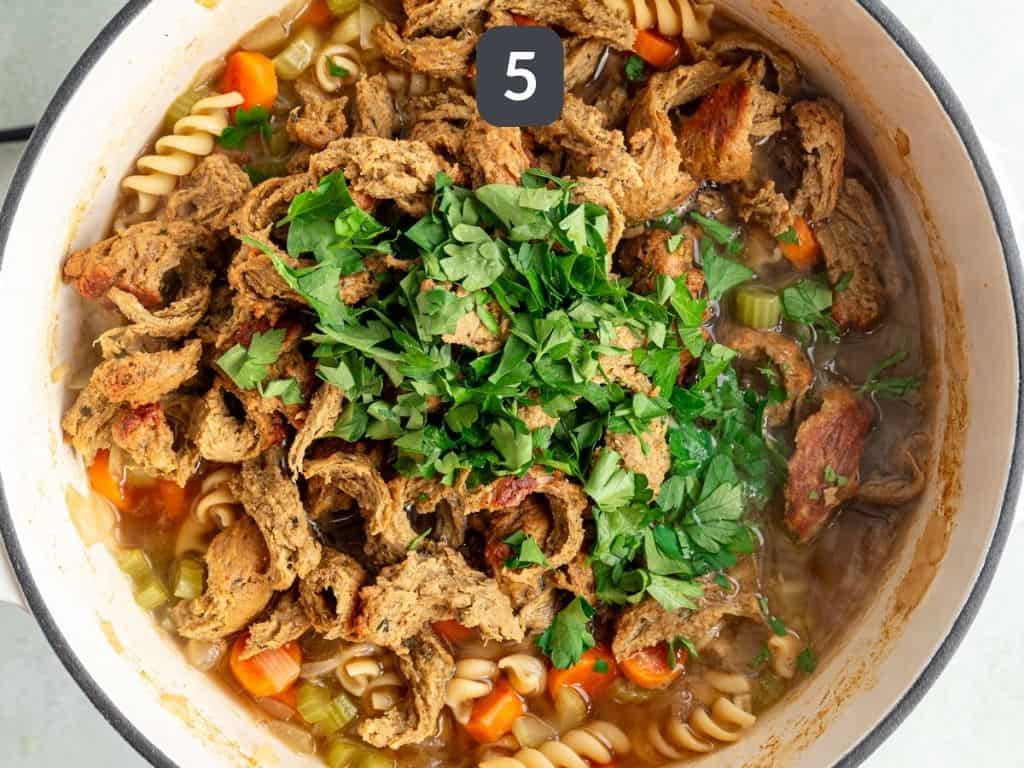 Vegan chicken noodle soup step 5 - stir in the chicken and parsley.