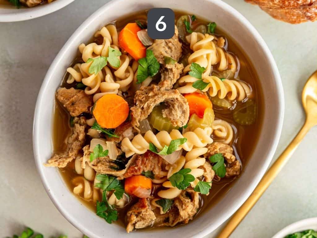 Vegan chicken noodle soup step 6 - serve with a garnish of parsley.