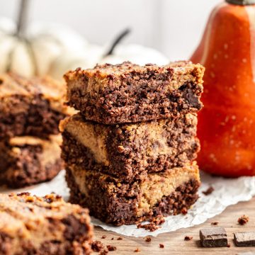 A stack of vegan pumpkin brownies on a sheet of parchment paper.