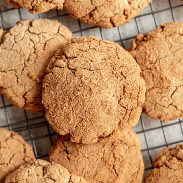 A pile of vegan gluten-free snickerdoodles on a cooling rack.