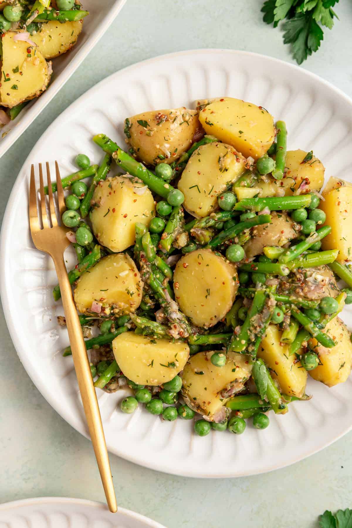 A plate of asparagus potato salad, with a fork, ready to eat.