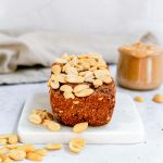 A loaf of peanut butter sweet potato bread with peanuts on top.