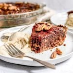 A plate of bourbon pecan pie with a bite removed and a scoop of ice cream.