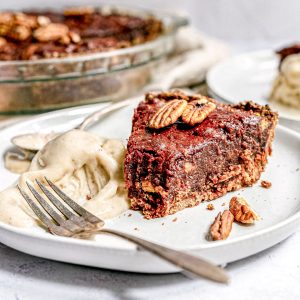 A plate of bourbon pecan pie with a bite removed and a scoop of ice cream.