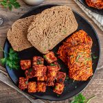 A plate of sweet potato hash browns, tempeh sausage, and toast.