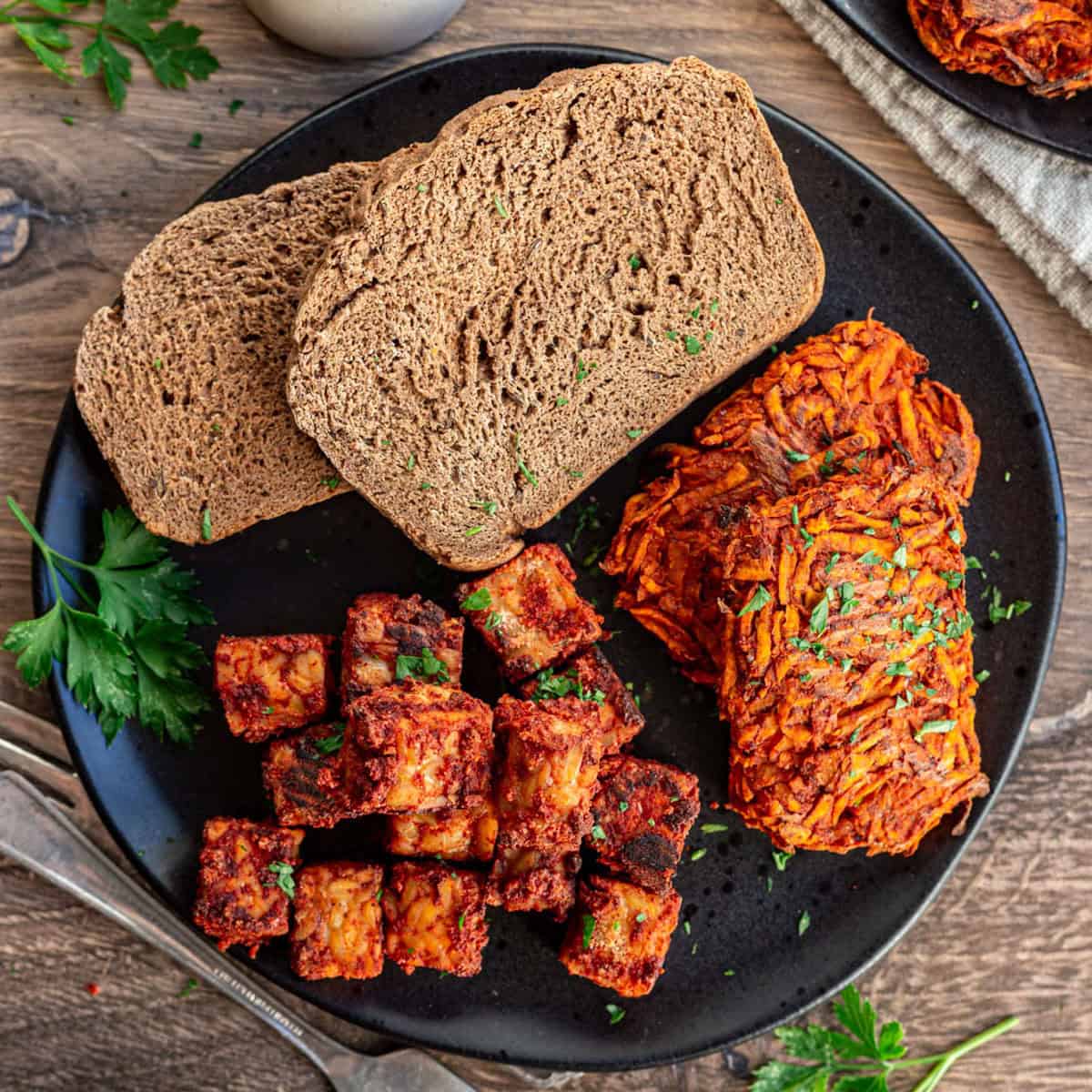 A plate of sweet potato hash browns, tempeh sausage, and toast.