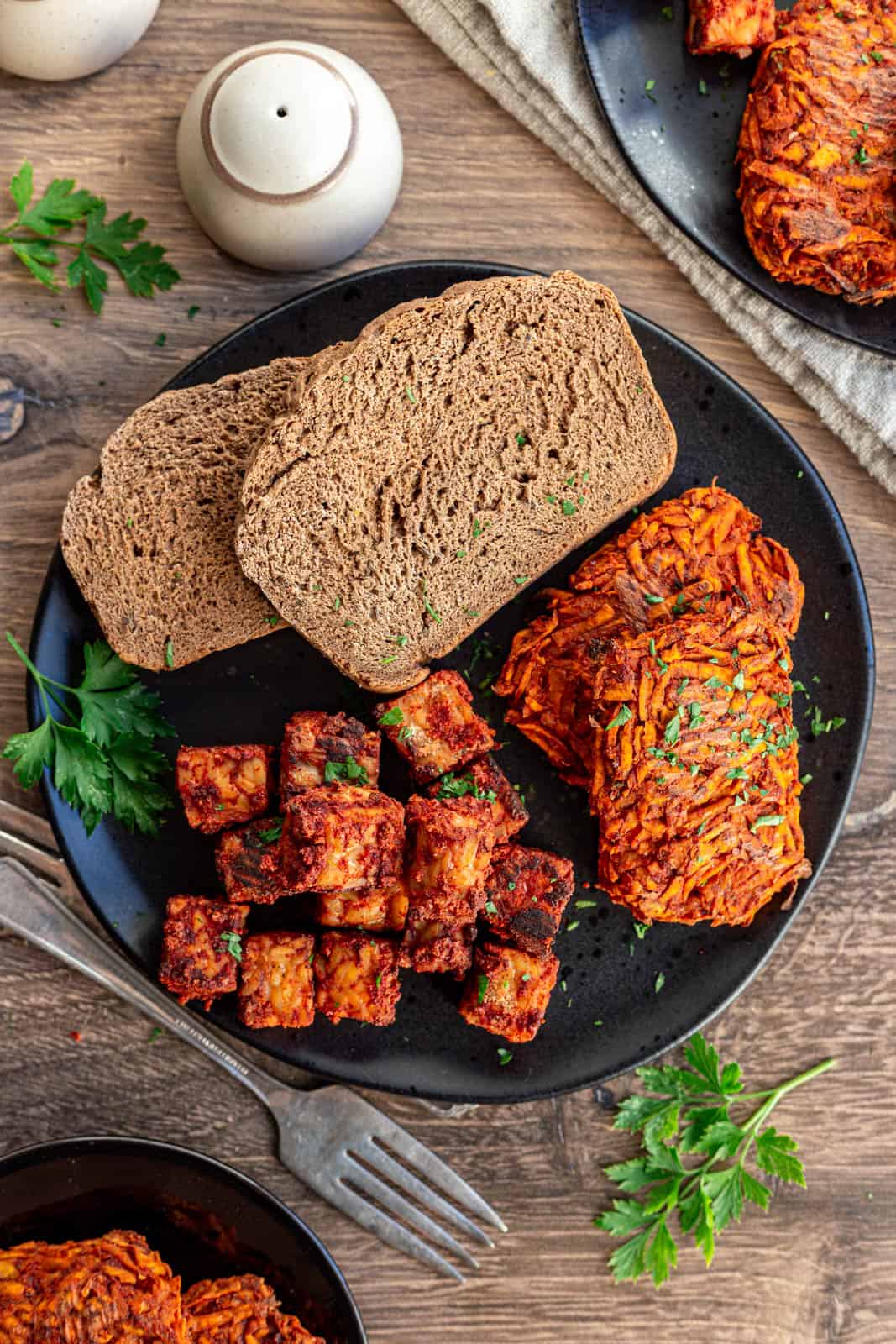 A plate of sweet potato hash browns, tempeh sausage, and toast.