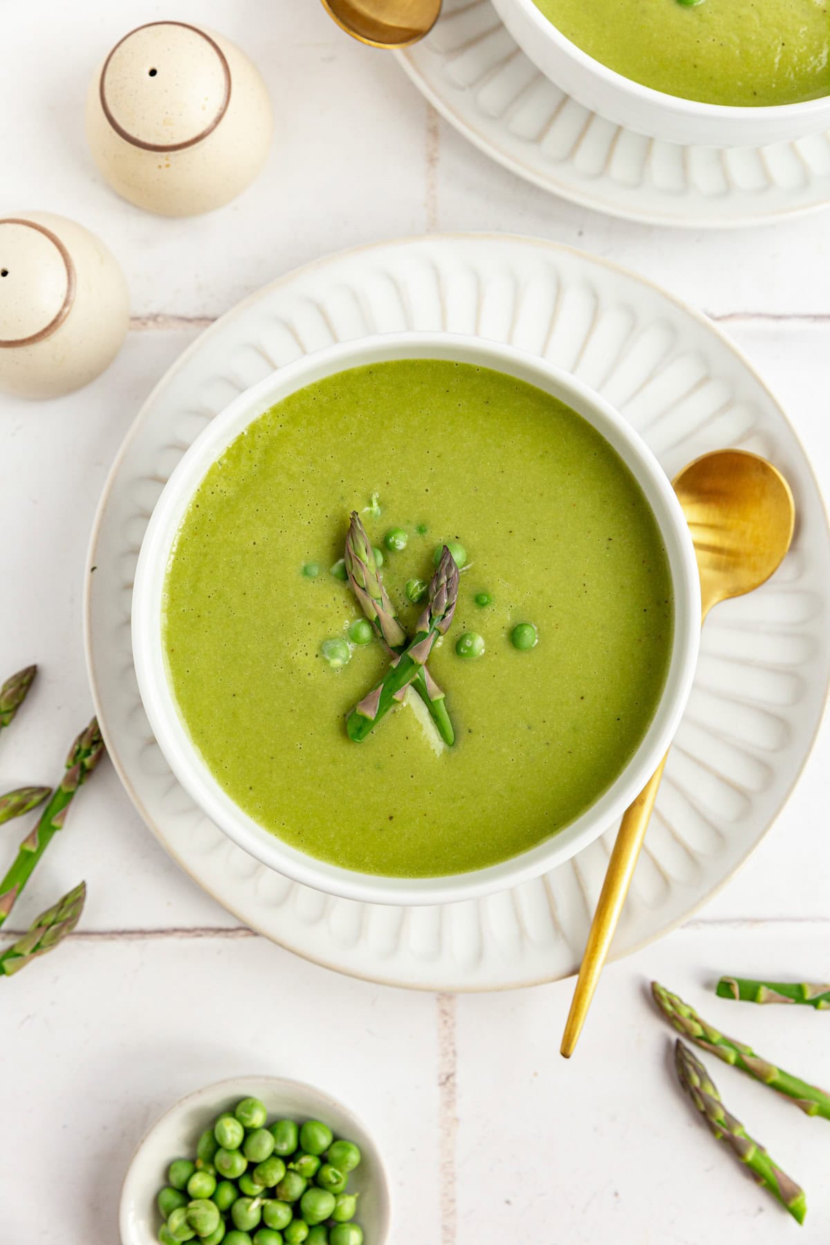 A bowl of Vegan Asparagus Soup on a plate, with a spoon, ready to serve.