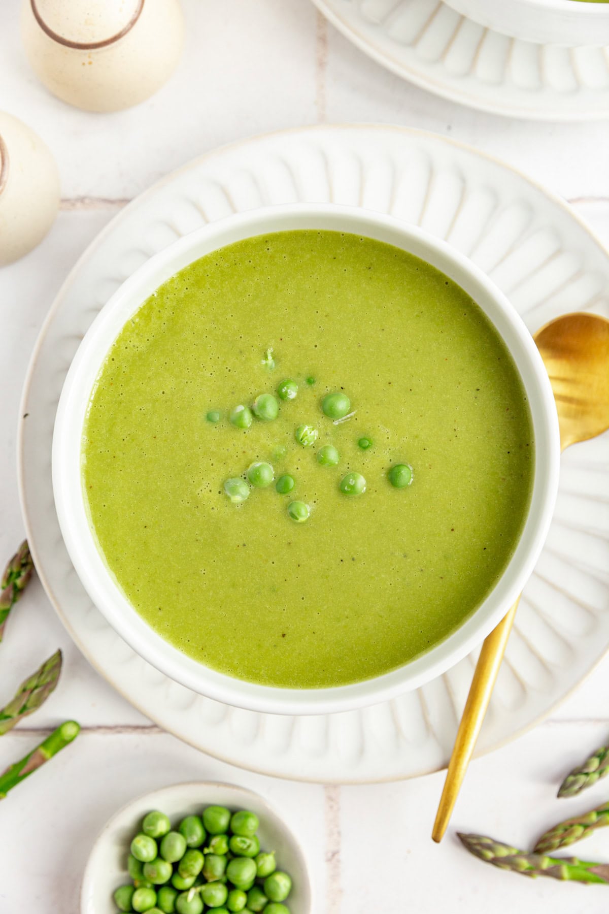 A bowl of Vegan Asparagus Soup, with a small dish of fresh peas on the side.