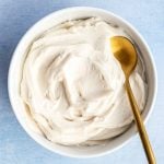 A bowl of vegan cream cheese frosting with a spoon.