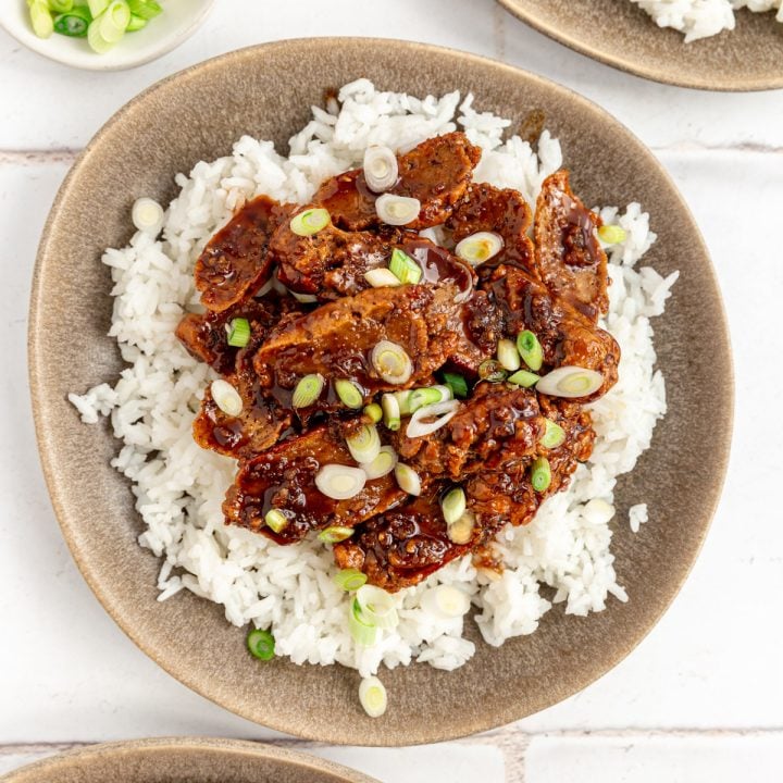A plate of Vegan Mongolian Beef, served over rice, topped with scallions.