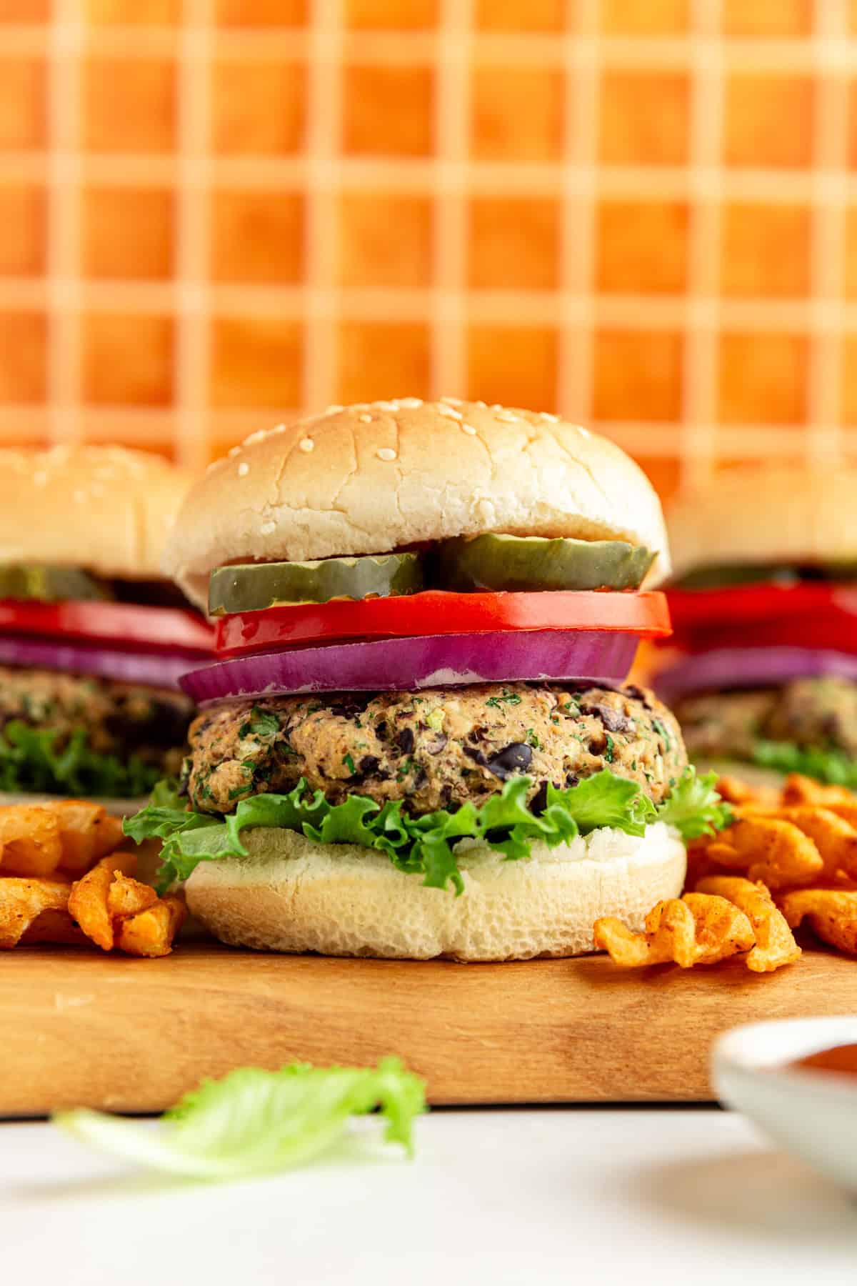 A Vegan Kidney Bean Burger on a bun with lettuce, onion, tomato, and pickles.