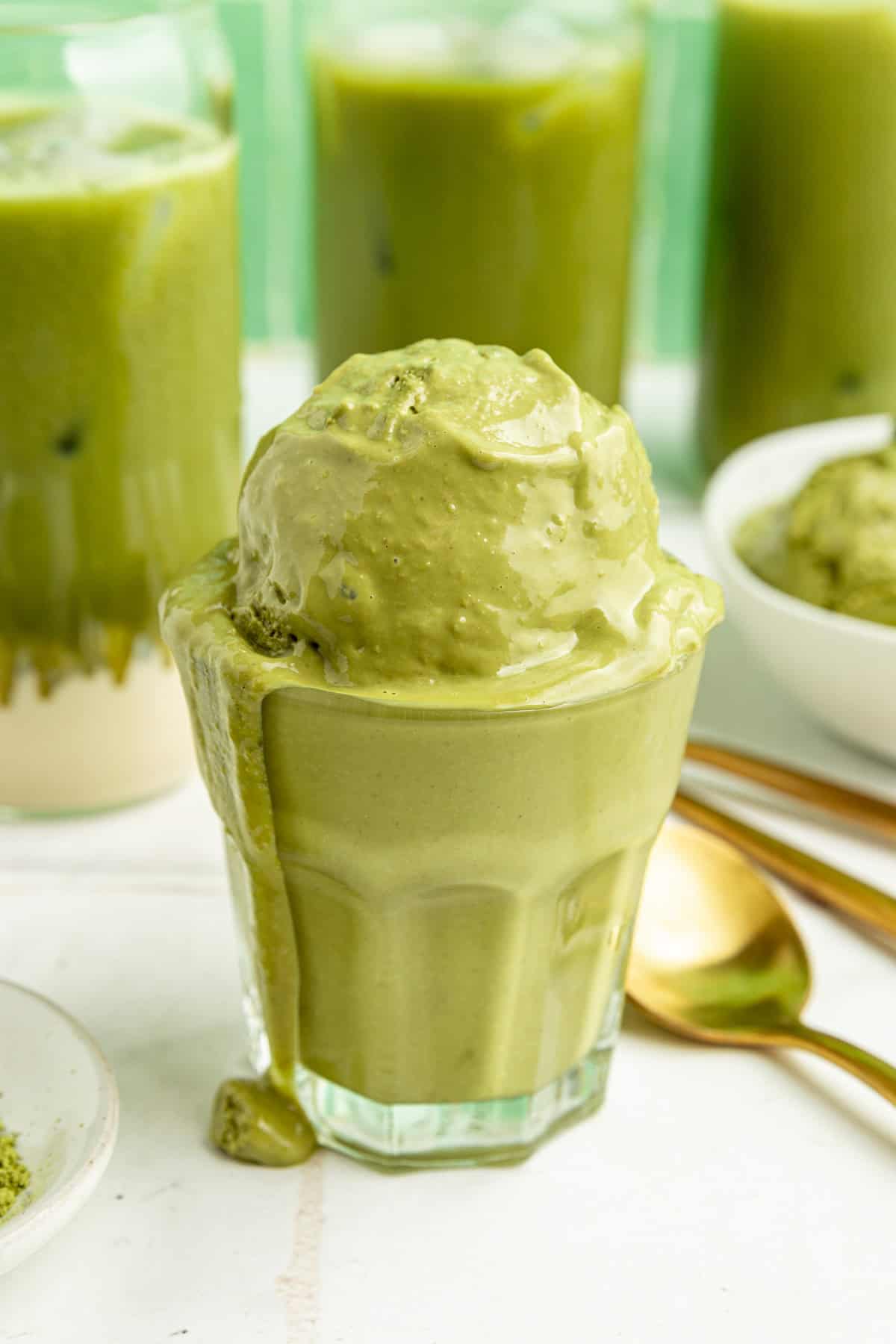 A glass filled with vegan matcha ice cream dripping down the sides.