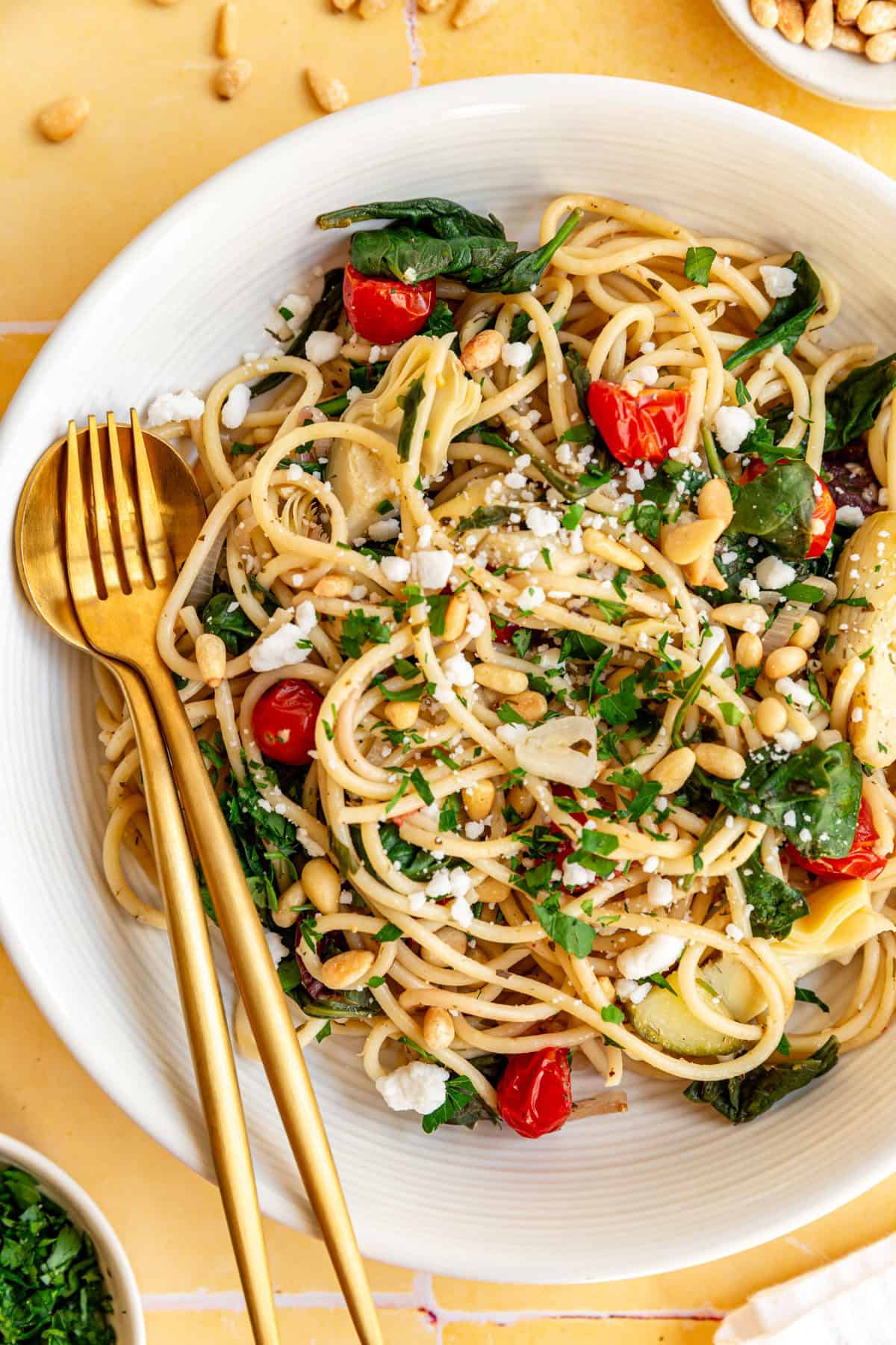 A bowl of vegan mediterranean pasta, with a fork and spoon.