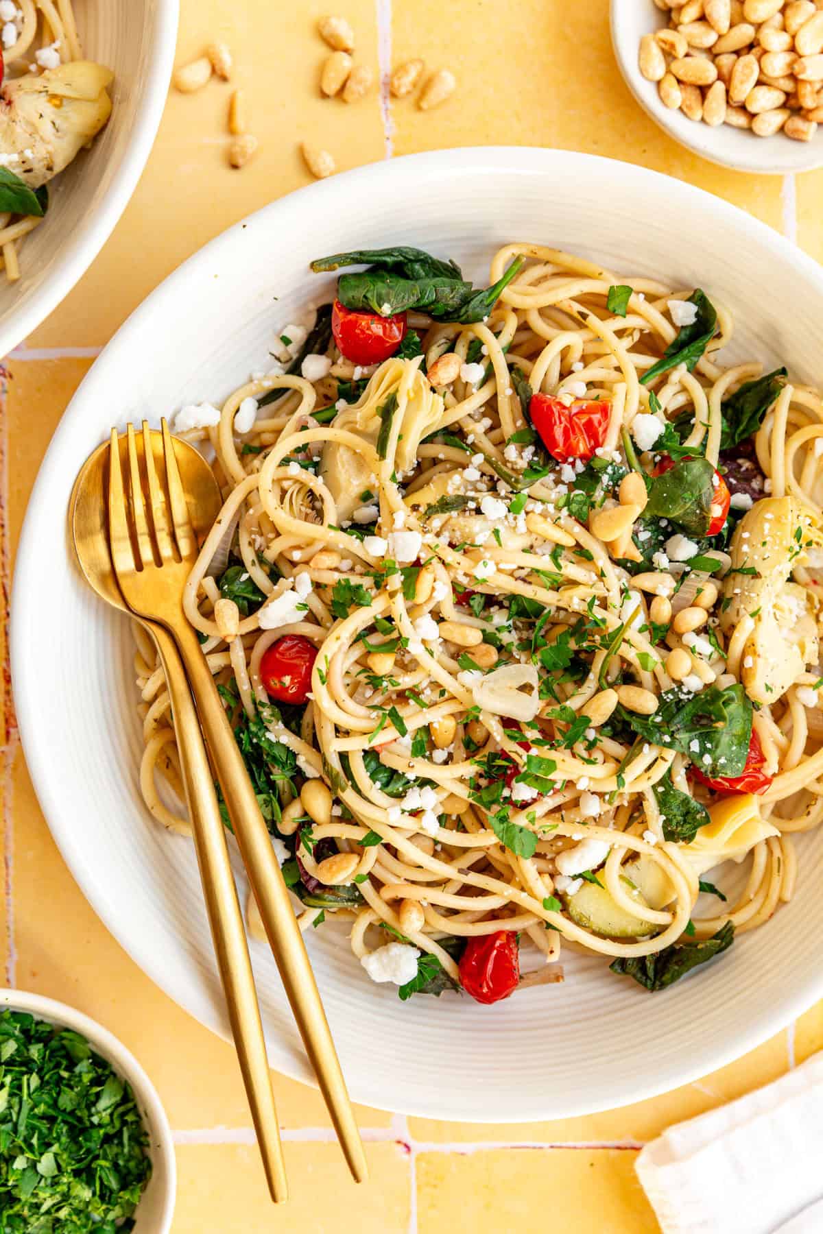 A bowl of vegan mediterranean pasta, with a fork and spoon, ready to serve.