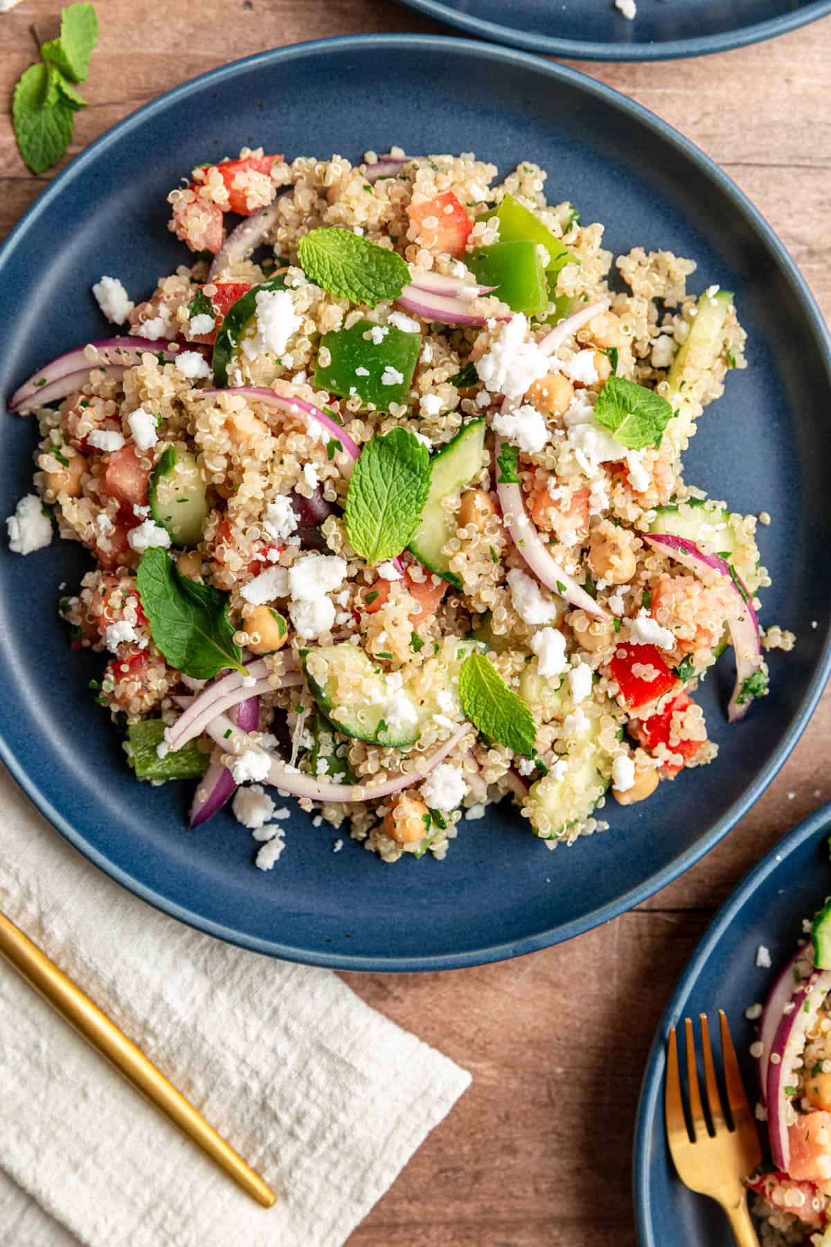A plate of mediterranean quinoa salad with a napkin and fork, ready to serve.