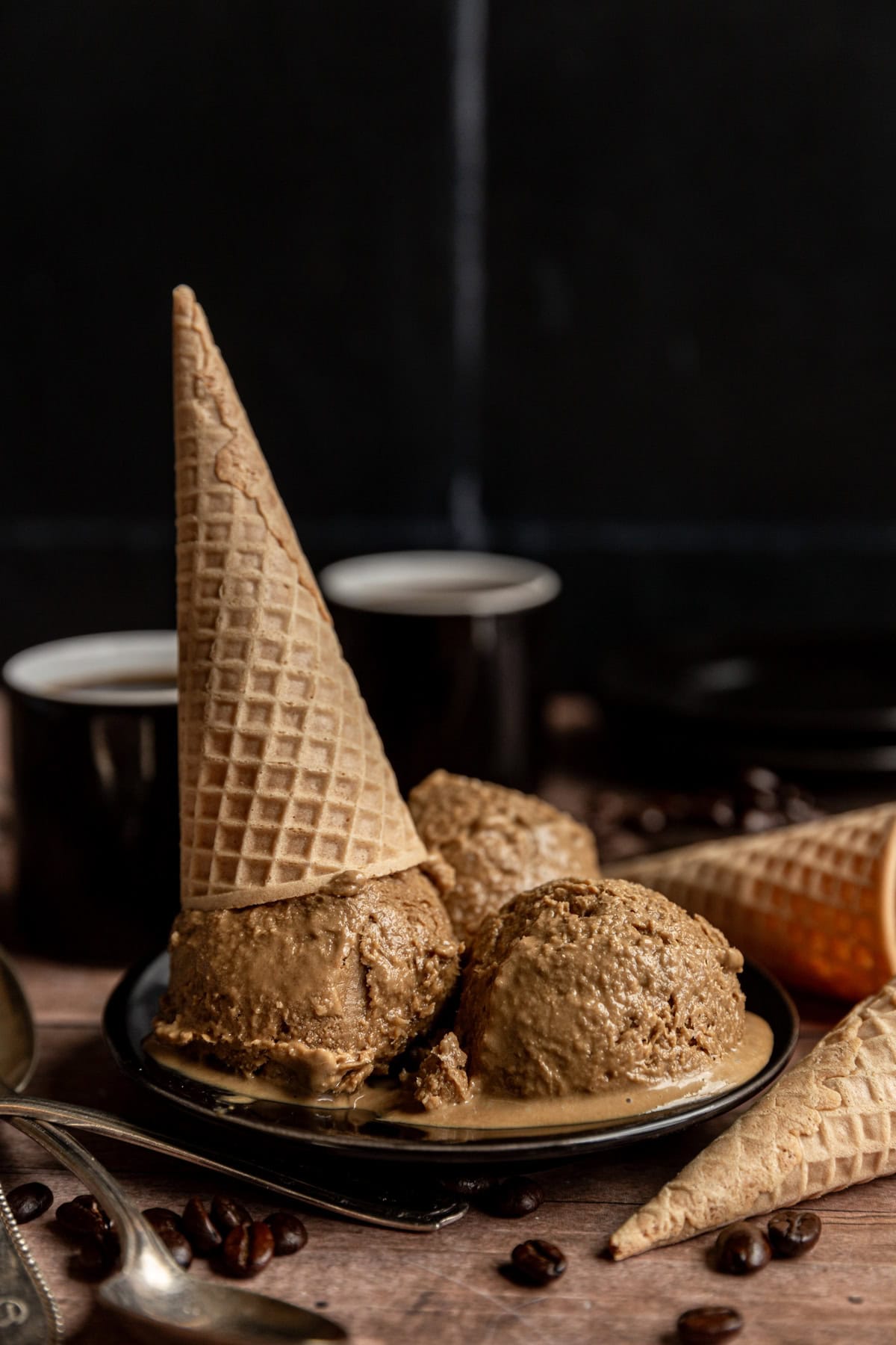 Three scoops of Vegan No Churn Coffee Ice Cream on a plate, with an ice cream cone on top.