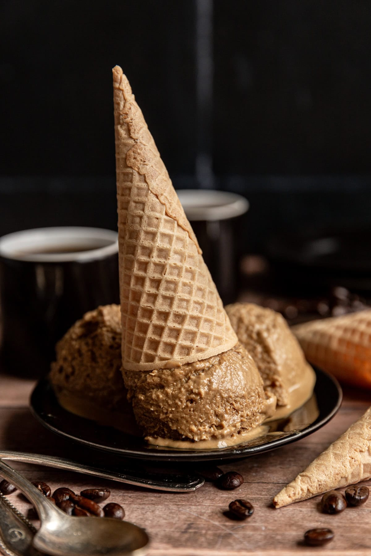 Three scoops of Vegan No Churn Coffee Ice Cream on a plate, with an ice cream cone on top.