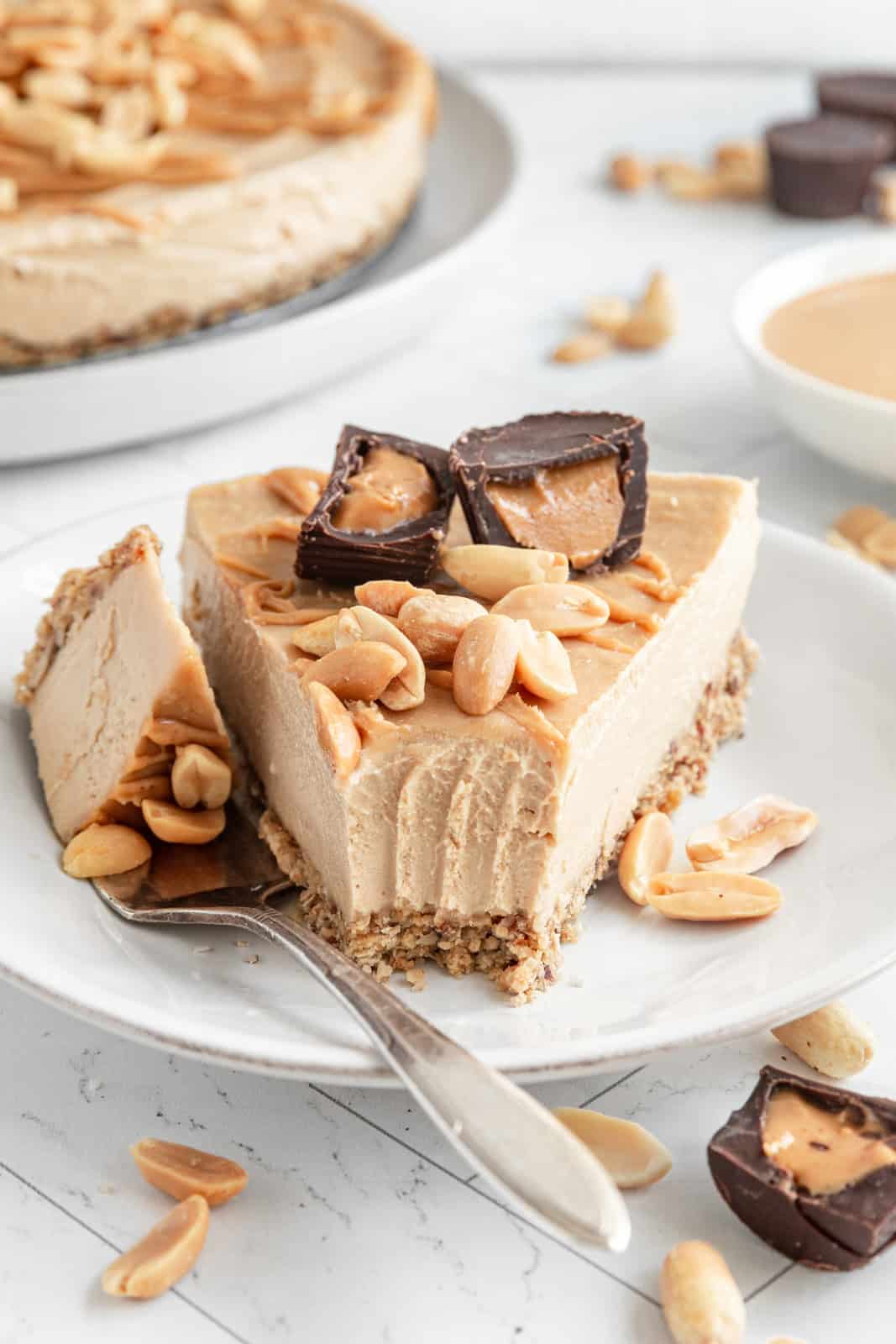 A slice of Vegan Peanut Butter Cheesecake with a bite taken.