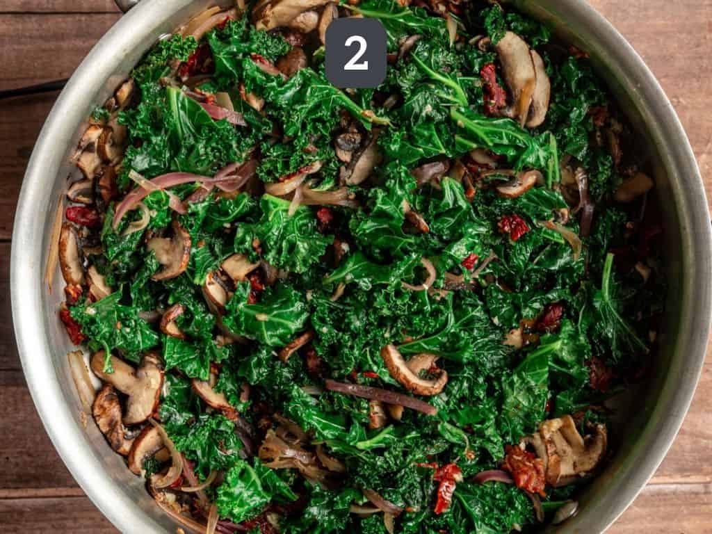 Kale, tomatoes, and mushrooms cooked in a pan.