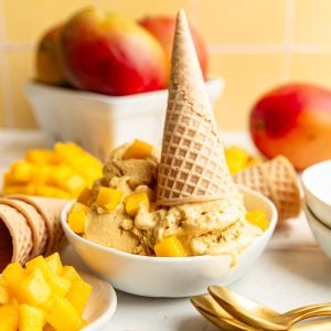 A bowl of no-churn vegan mango ice cream with an upside-down ice cream cone in the bowl.