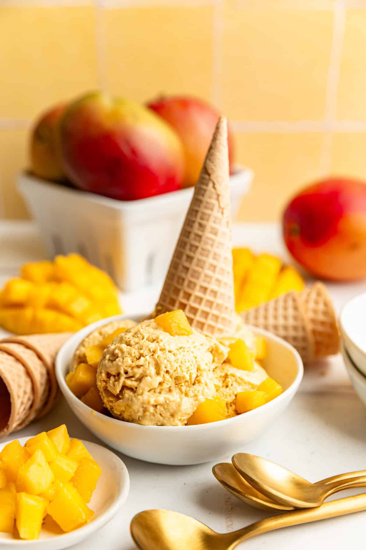 A bowl of no-churn vegan mango ice cream with an upside-down ice cream cone in the bowl.