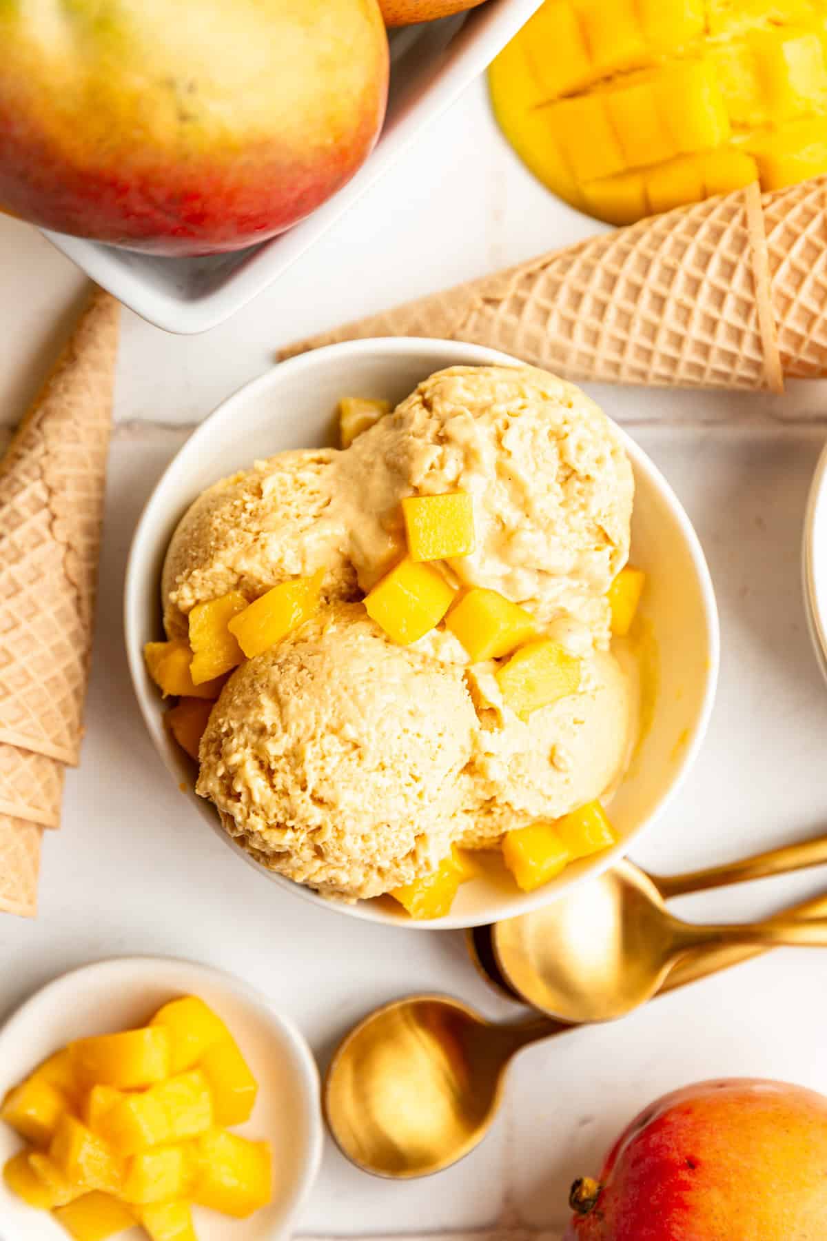 A bowl of vegan mango ice cream topped with fresh mango chunks.