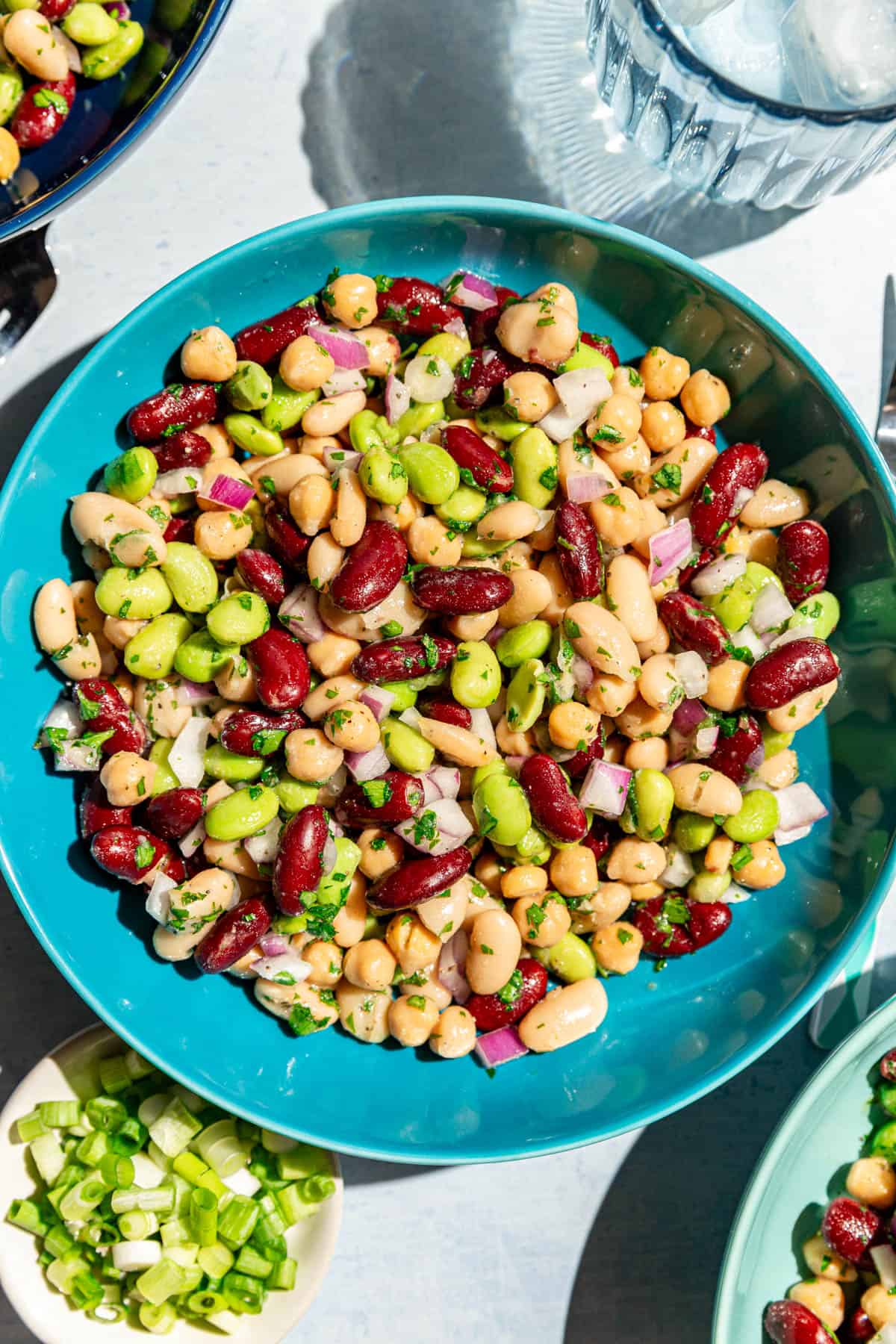 A bowl of vegan four bean salad with a glass of water.