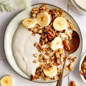 A plate of yogurt topped with banana walnut granola.