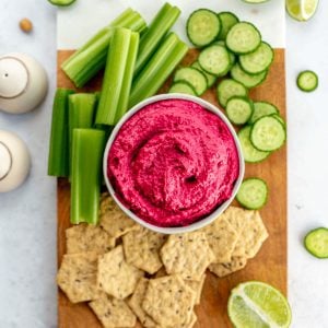 A tray of veggies, crackers, and a bowl of beet hummus.