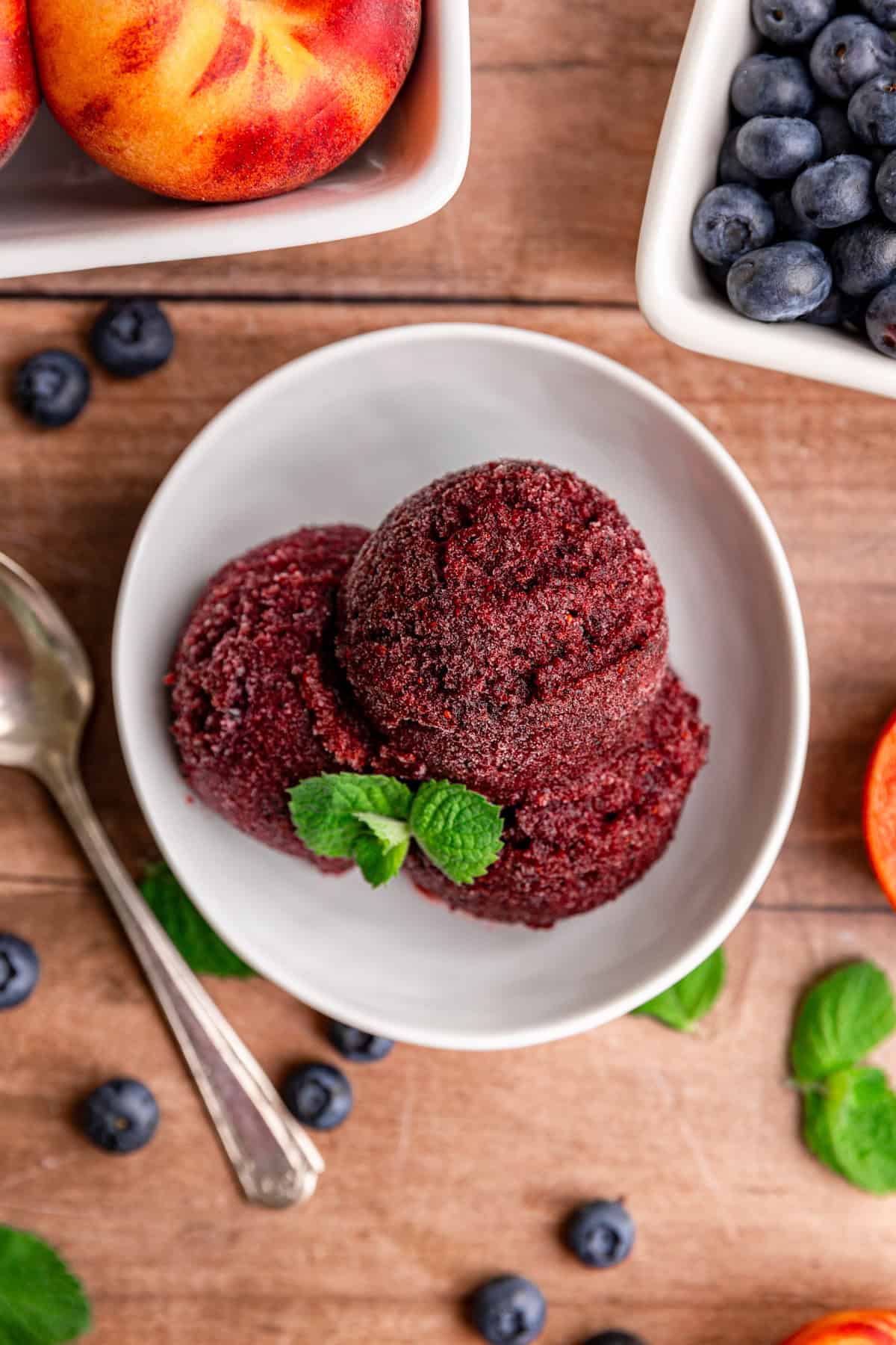 A top-down view of a bowl filled with three scoops of blueberry peach sorbet.